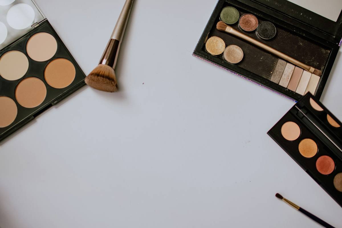 Wet cosmetic blending sponge tool being pressed into cheekbone for seamless foundation application